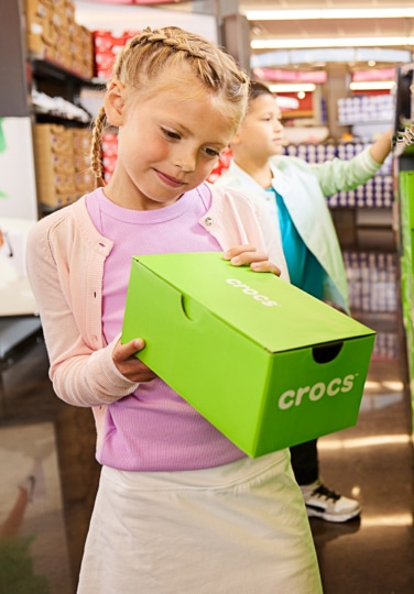 Little girl holding shoe box inside Famous Footwear store